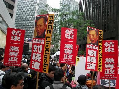 图一：民众在游行出发前的集会上，所持标语牌上书有“抗议重判刘晓波”、“立即释放刘晓波”。